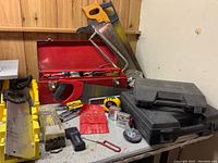 Overview of toolbox, hand saws, socket cases, measuring tape, wire brush and various small tools spread on tabletop