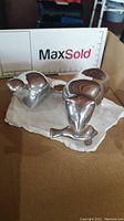 Photo of a silver-tone bear and fish sculpture on a rough, flat stone base. The bear and fish are smooth and polished, signed Hoselton.