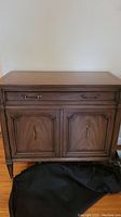 Front view of Malcolm wooden server showing drawer and cupboard doors with metal handles, some visible wear marks.