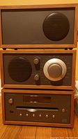Front view of stacked speaker, radio, and CD player units in wooden casing.