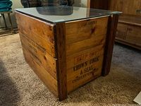 Angled view of the wooden crate showing corner metal reinforcements and glass top taped in place.