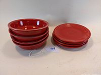 Stack of 4 red Fiesta cereal bowls next to 4 red Fiesta dessert plates.