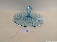 Blue depression glass center handled server shown flat and viewed from slight side angles to show pattern and handle details.