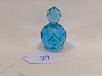 Blue faceted glass perfume or cologne bottle shown from front angle with stopper on.