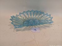 Blue opalescent glass oblong bowl with ruffled edges, starburst pattern, and slight iridescence.