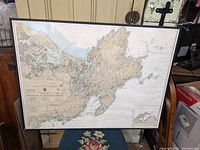 Framed nautical chart leaning against wall with part of the frame visible