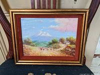 Full view of the framed oil painting showing El Chimborazo mountain, animals on a path, trees and houses.