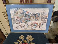Framed print artwork with blue mat and thin gold frame showing New Brunswick farm buildings and horse-drawn cart in muted winter colors.