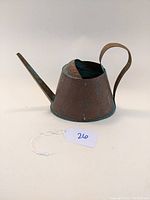 Side angle of vintage hammered copper watering can showing the conical body, long spout, curved handle, and patina.