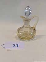 Side view of the yellow/topaz glass oil cruet showing the Yeoman pattern depressions, handle, and clear glass stopper.