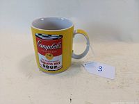 Front view of yellow ceramic mug with Campbell's Tomato Rice Soup label graphic and white interior.