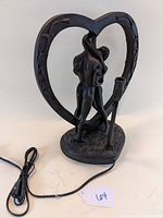 Front view of lamp showing nude couple embracing within heart-shaped frame with lamp socket on base