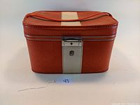 Front view of vintage red and white vinyl makeup travel case showing clasp lock and handle.