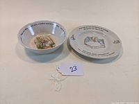 Set of two children's tableware items from Wedgwood Peter Rabbit collection, one plate and one bowl shown side by side on white background.