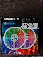 Front view of box showing 3 coiled LED strip lights displaying multicolor spectrum and remote controller icon.