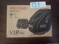 Photo of the boxed Rexing V1P Pro dash cam device showing brand, model, and advertised features like built-in WiFi and GPS logger.