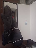 Pair of black heated mittens displayed in a white box. Mittens have a red power button and reflective strip details visible on top side. Medium size indicated.