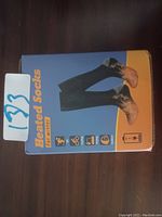Photo of a box labeled 'Heated Socks' showing an image of black socks and care/use icons for winter activities.