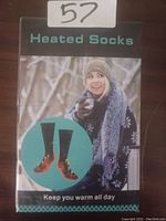 Photo of the packaged heated socks showing branding and image of a woman dressed for cold weather.