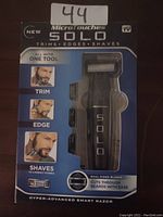Photo of the Micro Touch Solo hyper-advanced smart razor in its original packaging, highlighting trimming, edging, shaving capabilities and dual-sided blades.