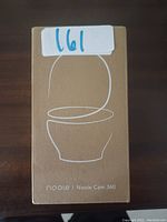 Photo of a brown cardboard box with white line art of a Nooie Cam 360 camera and the product text.