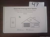 White box packaging of Smart Wi-Fi Garage Door Opener model RSG100 showing device image and house garage illustration with Wi-Fi symbol.