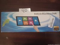 Photo of the Vehicle Blackbox DVR packaging showing product name and touchscreen interface illustration including icons for camera, playback, setting, photo, and shutdown.