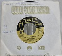 Close-up photo of a 45 RPM vinyl record by Foreigner titled "I Want to Know What Love Is" on Atlantic Gold Standard label with white paper sleeve.