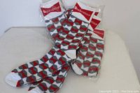 Four pairs of men's crew socks in plastic packaging, showing the geometric pattern and Budweiser branded cuff