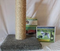 Photo showing the cat scratching post with carpeted base and sisal-wrapped post, the packaged dog training collar receiver collar in the background, and the training collar box.