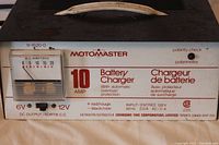 Front view of Motomaster 10 amp battery charger showing ammeter, brand logo, and connection details.