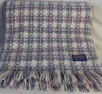Folded Pendleton wool throw blanket showing basketweave pattern in plum, mauve, steel blue, and off-white base with fringed edge and brand label.
