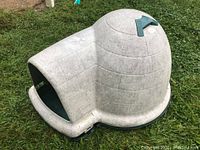 Side view of the igloo dog house showing entrance and dome shape, off-white plastic with light dirt marks.