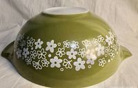 View of the bottom of the medium green Pyrex bowl showing white floral pattern around the outside and flat white base