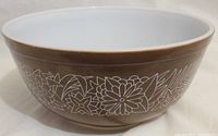 Side view of the brown mixing bowl showing white floral and leaf design pattern