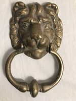 Front view of solid brass lion head door knocker with ring in mouth.