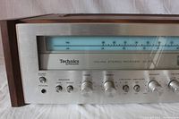 Front right side of the receiver showing power switch, headphone jack, speaker toggles, bass, treble, low/high filter knobs, balance, and volume knob with brushed aluminum face and wood tone case.