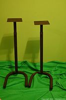 Full view of both adjustable speaker stands showing their height and flat top plates against a green backdrop.
