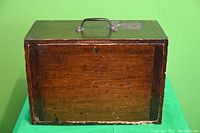 Closed view of antique wooden toolbox with carrying handle and removable door featuring an antique lock with no key.