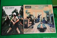 Front covers of two vinyl albums: The Verve - Urban Hymns and Oasis - Definitely Maybe on a green background.