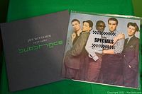 Both vinyl album covers shown side by side: Joy Division's Substance (dark gray with green text) and The Specials with band photo and checkerboard.