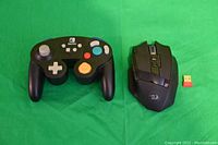 Nintendo Switch GameCube style controller and Redragon Sniper Pro wireless gaming mouse displayed with USB receiver on green background.