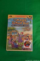 Front cover of the sealed DVD box showing the title 'The Magic School Bus The Complete Series' with artwork of Ms. Frizzle and her class by the school bus.