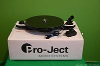 Front view of turntable on Pro-Ject Audio Systems box showing power adapter and cable