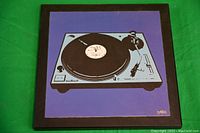 Photo of a square wood backed modern art piece depicting a Technics 1200 turntable on a purple background.