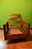 Front view of the walnut lounge chair frame showing geometric wooden frame and armrests.