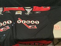 Two black Vegas Gamblers hockey jerseys laid out showing front with Vegas logo and graphics