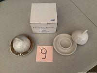Top-down photo showing two white ceramic butter dishes with dome covers and plates, alongside original Princess House box and a pink label with '9'.