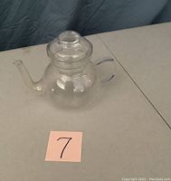 Single clear crystal tea pot photographed from the front, showing the body, spout, handle, and lid with knob.