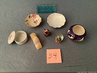 Overview of all assorted collectibles including jewelry bowls, cat figurine, snow globe, Sphinx and decorative plate.